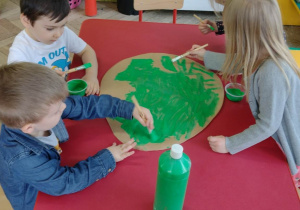 Dzieci z grupy Sówki malują wielką zieloną pisankę