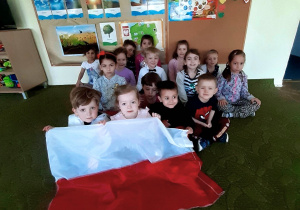 Dzieci trzymają materiałową flagę Polski