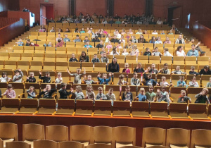 Dzieci siedzą w pierwszych rzędach na Sali koncertowej