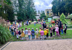 Dzieci stoją w kole na placu przedszkolnym i śpiewają piosenką