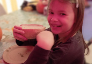 Dziewczynka z uśmiechem zjada bułkę