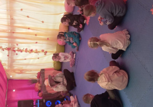 Dzieci siedzą w kole i słuchaj opowiadania o Leśnej Zagrodzie Gadów Animatorki