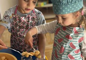 chłopiec i dziewczynka nakładają jabłka do słoików