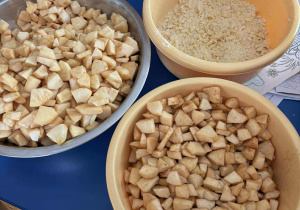 na stoliku stoja miski w których są pokrojone w kostkę jabłka