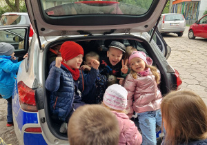 Dzieci z grypy Misiów siedzą w bagażniku radiowozu