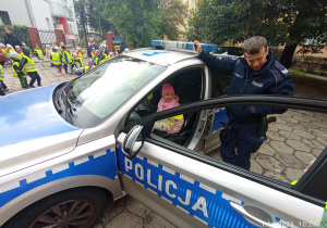 Hania siedzi w radiowozie obok stoi Pan Policjant