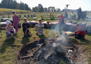 dzieci pieką kiełbaski przy ognisku