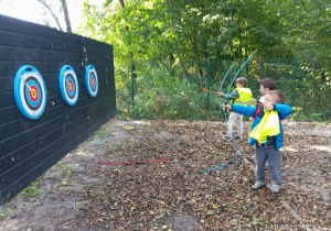 Chłopcy strzelają z łuku do tarczy