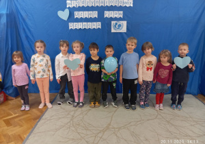 Zdjęcie grupowe dzieci z grupy Kotki na tle niebieskim tle z białym napisem Międzynarodowy Dzień Praw Dziecka