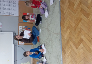 Dzieci siedzą na dywanie i słuchają opowiadania o emocjach.