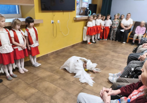 Dzieci śpiewają a Nela jako Biały Orzeł "upada na podłogę" odgrywając swoją rolę.