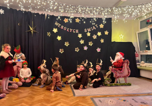 Dzieci jako renifery z grupy Misiów ciągną na saniach Mikołaja , obok stoi pani Mikołajowa, grupa Misiów