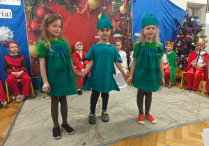 Dzieci z grupy Sówek stoją w strojach choineczek recytują wierszyki