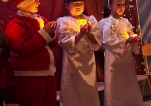 Dzieci z grupy Sówki podczas występu, trzymają światełka w dłoniach