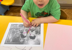 Chłopiec koloruje kartkę.