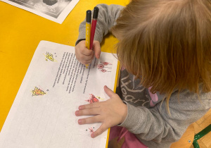 Dziewczynka koloruje kartkę.