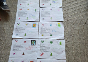 Na dywanie leżą kartki ozdobione przez dzieci z grupy Misiów