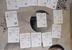 Na dywanie leżą kartki ozdobione przez dzieci z grupy Sowy