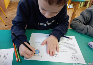 Dziecko rysuje znaczek na kartce