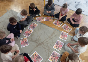 Dzieci z grupy Sowy siedzą na dywanie w kole a przed nimi ich gotowe prace