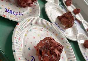 Na papierowych talerzykach leża papierowe pączki.