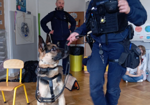 Policjantka prezentuje dzieciom umiejetności policyjnego psa.