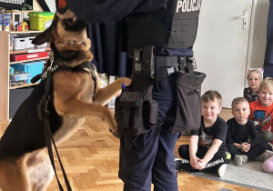Policjantka pokazuje dzieciom jak ćwiczy z psem.