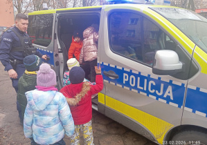 Dzieci oglądają policyjny radiowóz.