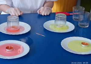 na talerzu ustawione są małe świeczki pod przezroczystymi szklankami