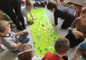 Dzieci uczą się sprzątać po psie na macie edukacyjnej.