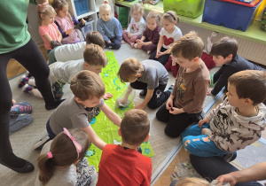 Grupa dzieci uczy się sprzątać po psie podczas zabawy.