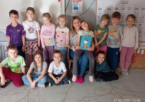 Pamiątkowe zdjęcie dzieci z grupy Sówki razem z czytająca mamą.