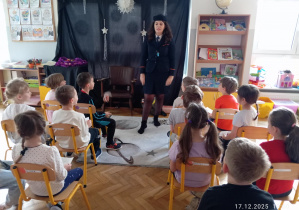 Dzieci siedzą na krzesełkach jak w pociągu a przed nimi stoi Pani kierownik pociągu ubrana w mundur.