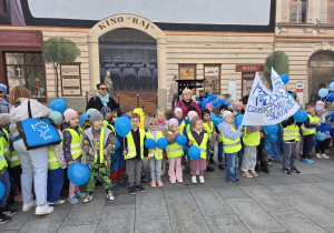 Dzieci stoją trzymając niebieskie balony.