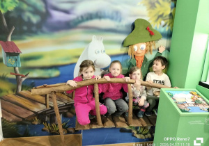 Grupa Kotków pozuje do pamiątkowego zdjęcia na tle ekspozycji związanej z Muminkami.