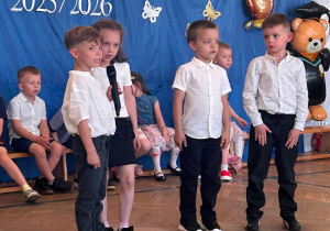 Dzieci w odświętnych strojach uczestniczą w uroczystości zakończenia przedszkola.